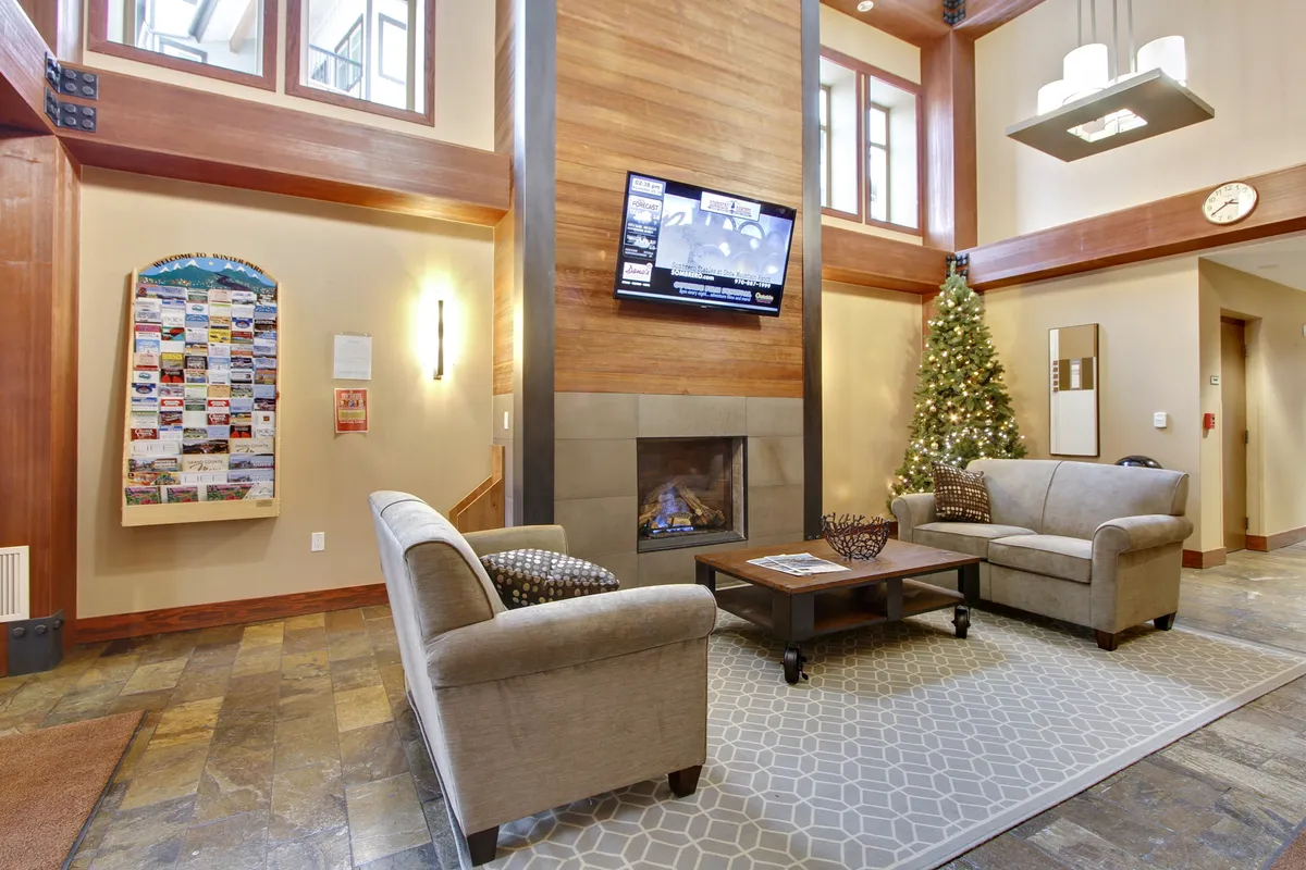A warm and inviting lobby scene centered around a stone fireplace, with comfortable seating, festive décor, and an atmosphere that invites relaxation and socializing. The space feels like a welcoming retreat after a day outdoors.